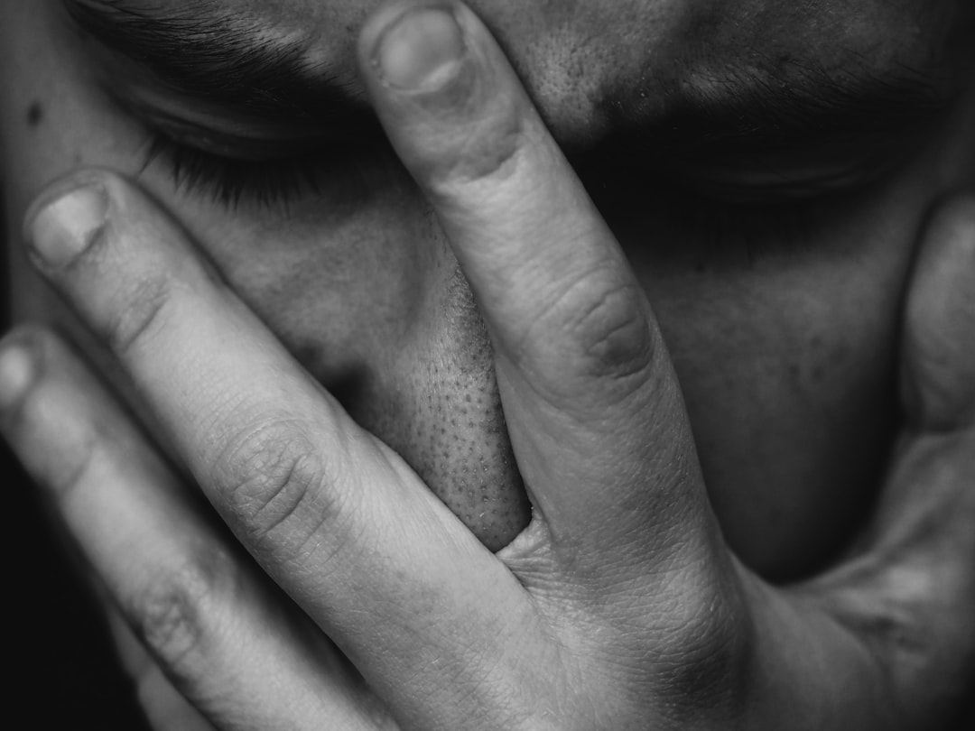 Photo by Adrian Swancar grayscale photo of person placing hand on face